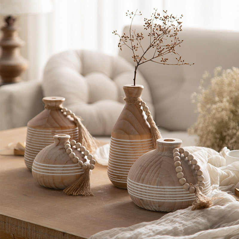Four natural wood bead and tassel vases styled with dried branches