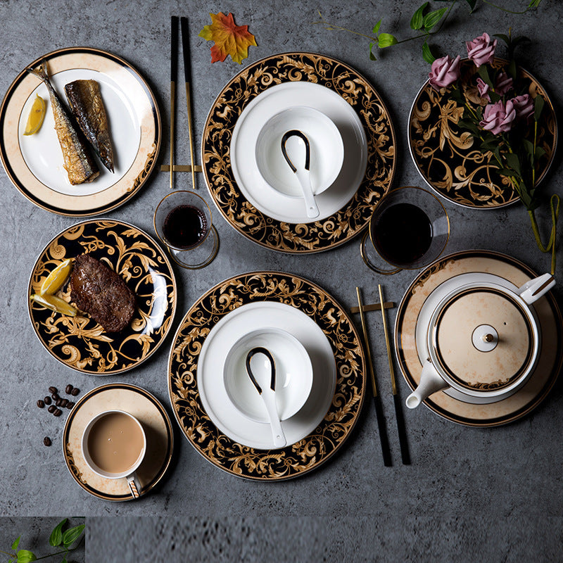 Black and gold bone china dinnerware overhead table setting with ornate plates, bowls, cups and teapot