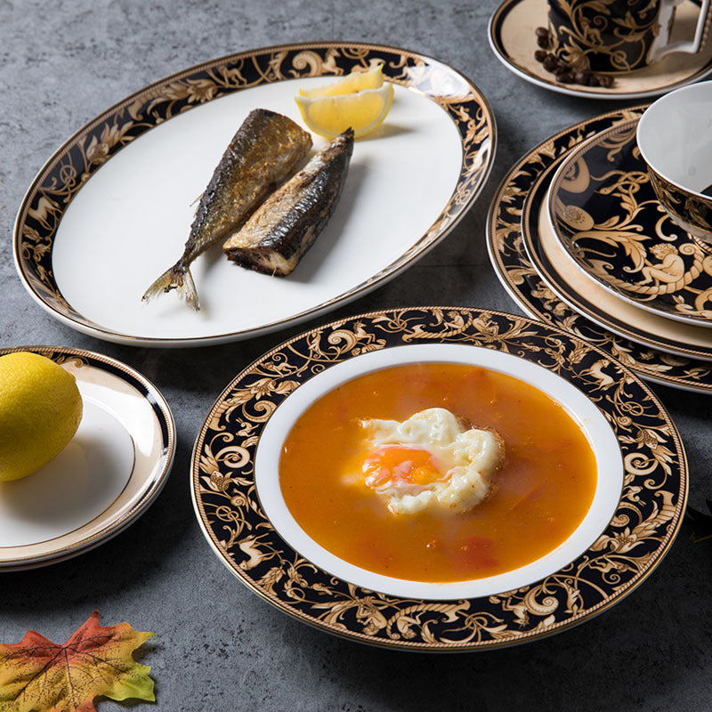 Black and gold bone china formal dining table setting with ornate dinner plates and soup plate