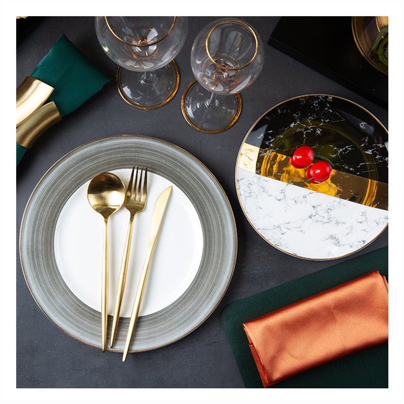 Black and white marble bone china place setting with grey dinner plate, gold flatware and dark green table linens