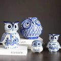 Blue and white owl figurine collection on dark wood