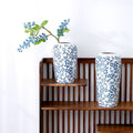 Blue and white floral cylinder vases styled together on a wood shelf