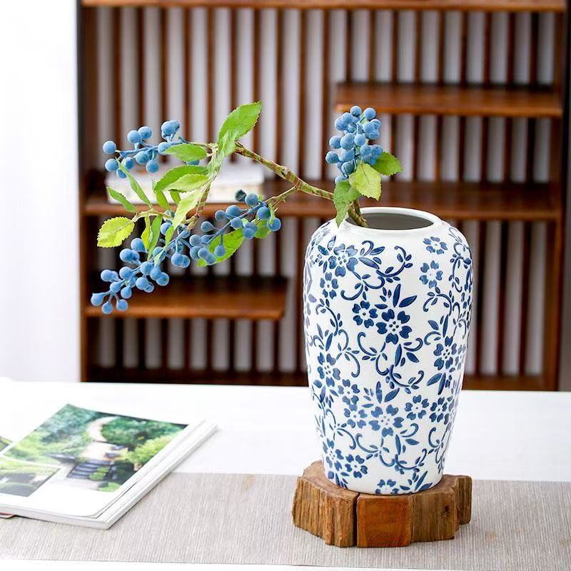 Small blue and white floral cylinder vase styled with berry branches