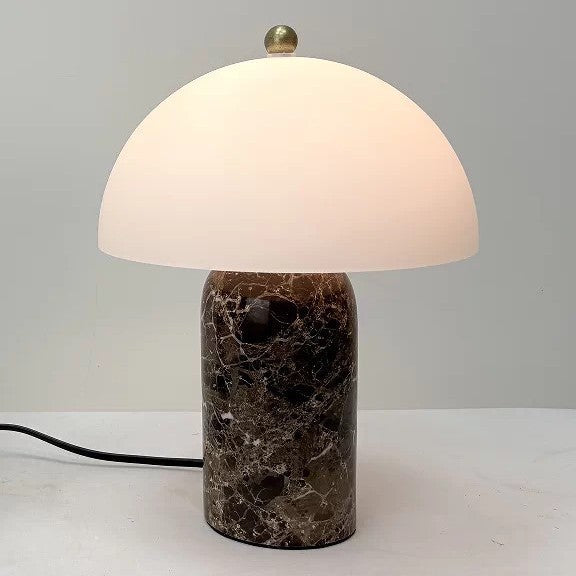 Brown marble cylinder mushroom table lamp glowing warmly on a white surface