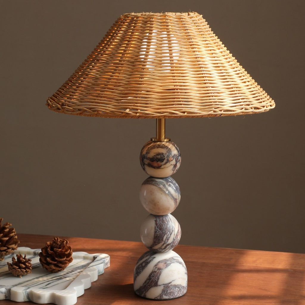 Warm glowing rattan shade over stacked Bvlgari-vein stone spheres