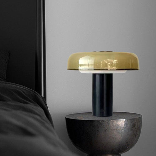 Amber glass dome table lamp with black metal base on sculptural side table