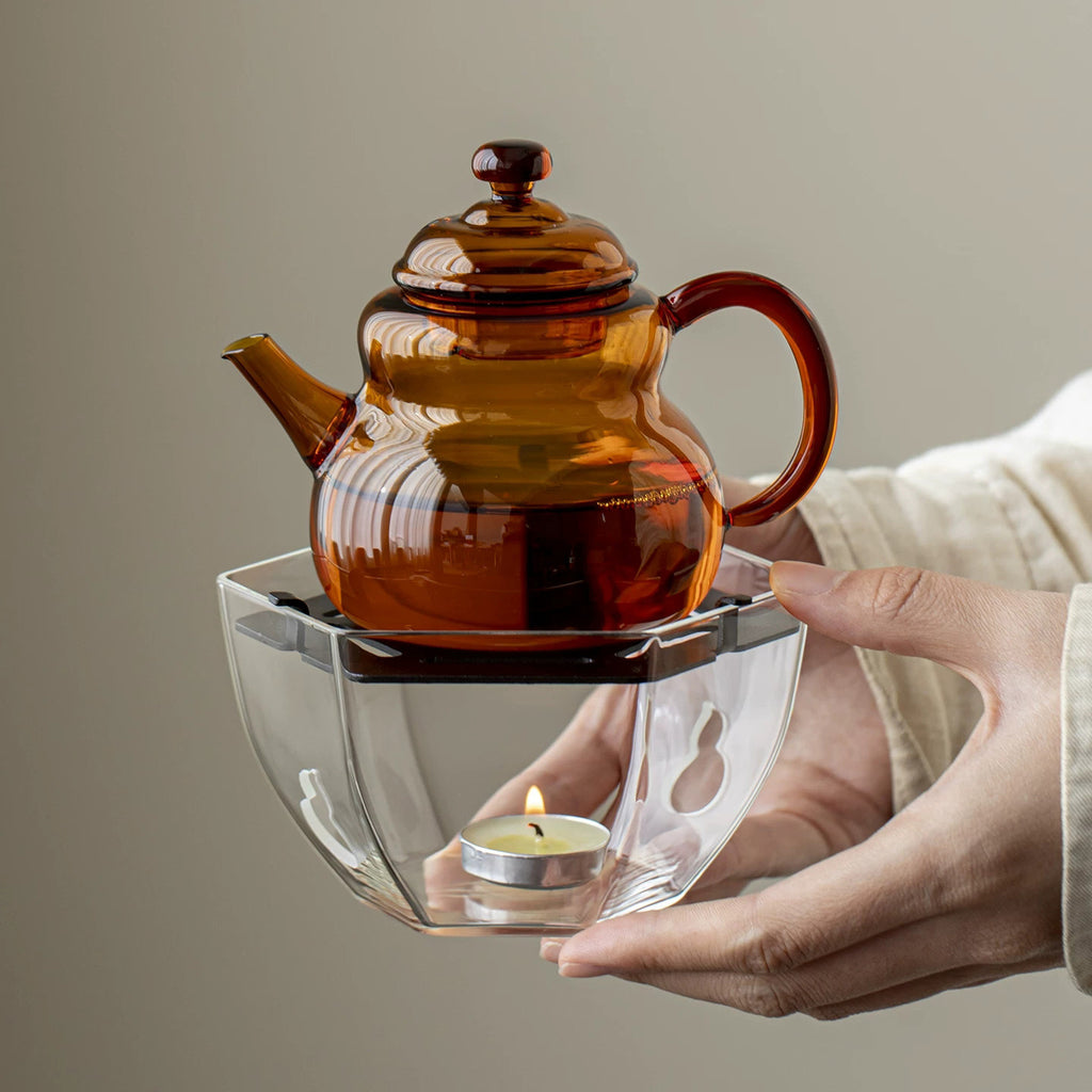 Amber borosilicate glass teapot warming over tealight candle