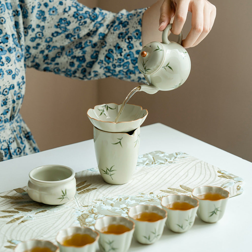 Hand-painted bamboo ceramic teapot pouring tea through a Gongfu tea filter