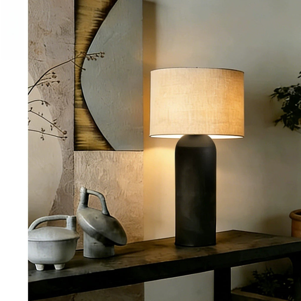 Large black cylinder table lamp with linen shade on sculptural console