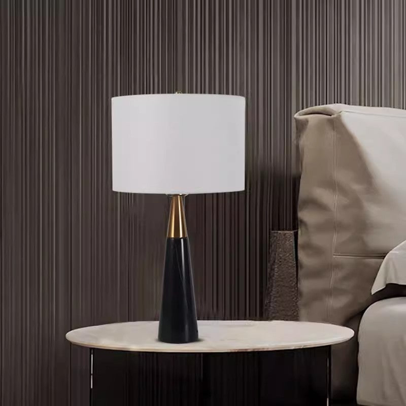 Tall black tapered marble table lamp with brass neck in modern bedroom
