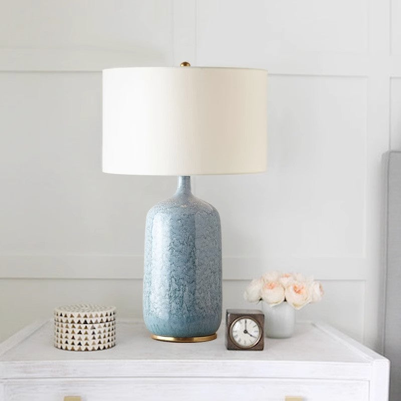 Blue ceramic lamp styled on a white console with flowers and clock