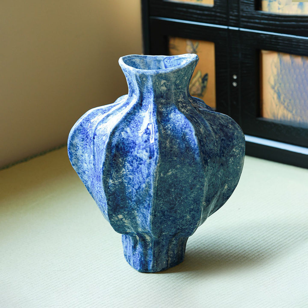 Blue sculptural ceramic vase showing faceted ribbed body and glossy glaze