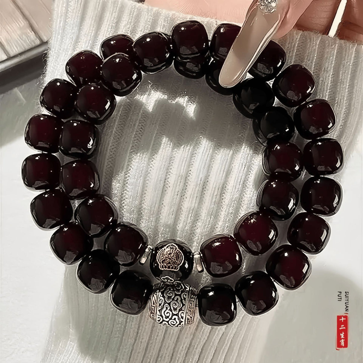Close-up of glossy dark red Bodhi root double-wrap bracelet with engraved guardian Buddha bead and carved metal centerpiece