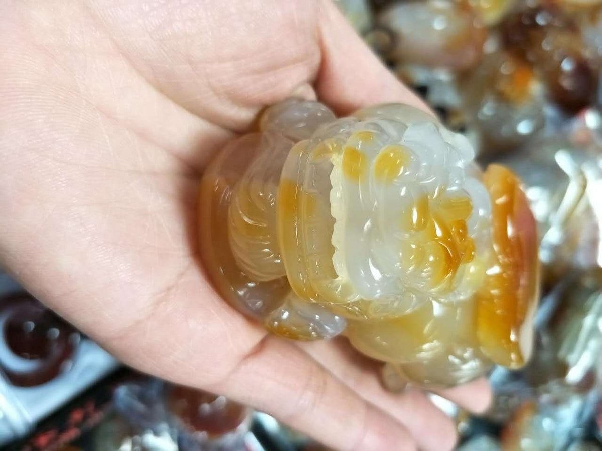 Hand-polished agate Pixiu palm piece with translucent honey coloring
