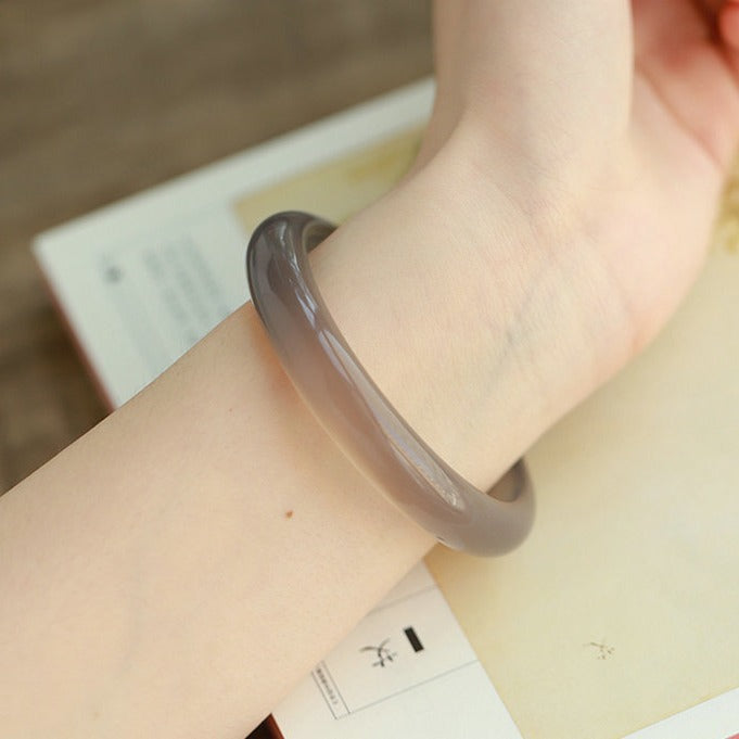 Natural smoky gray chalcedony agate bangle showing warm taupe-gray translucency