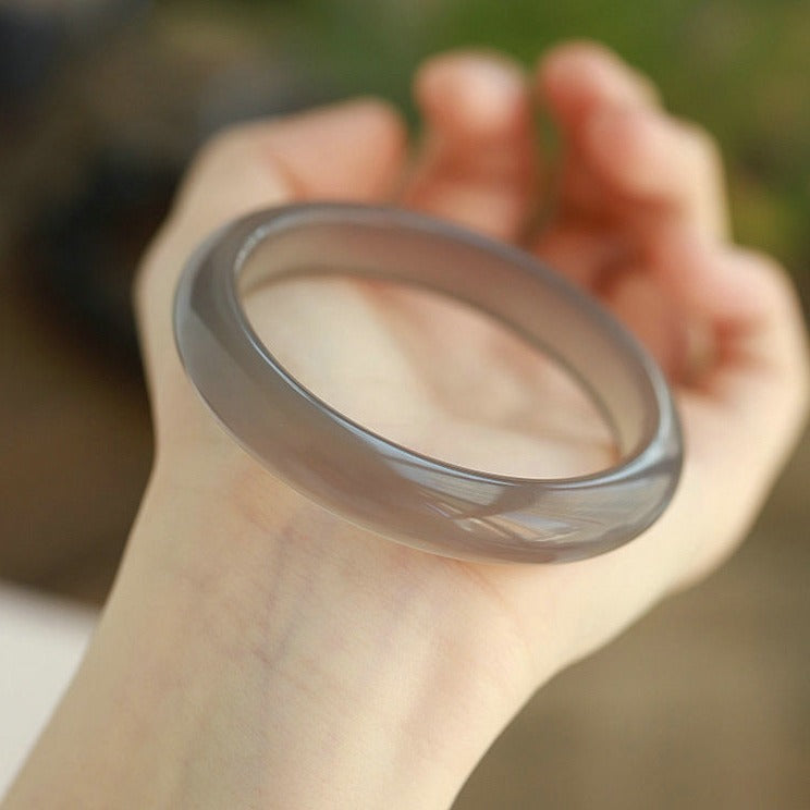 Natural smoky gray chalcedony agate bangle showing warm taupe-gray translucency