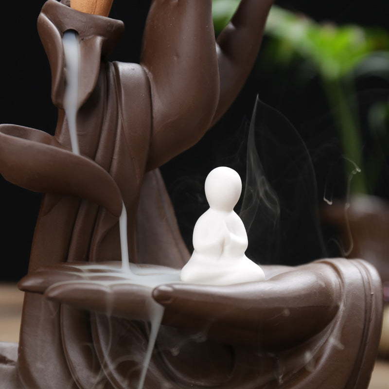 Close-up little white monk figure and descending smoke on Buddha hand incense burner
