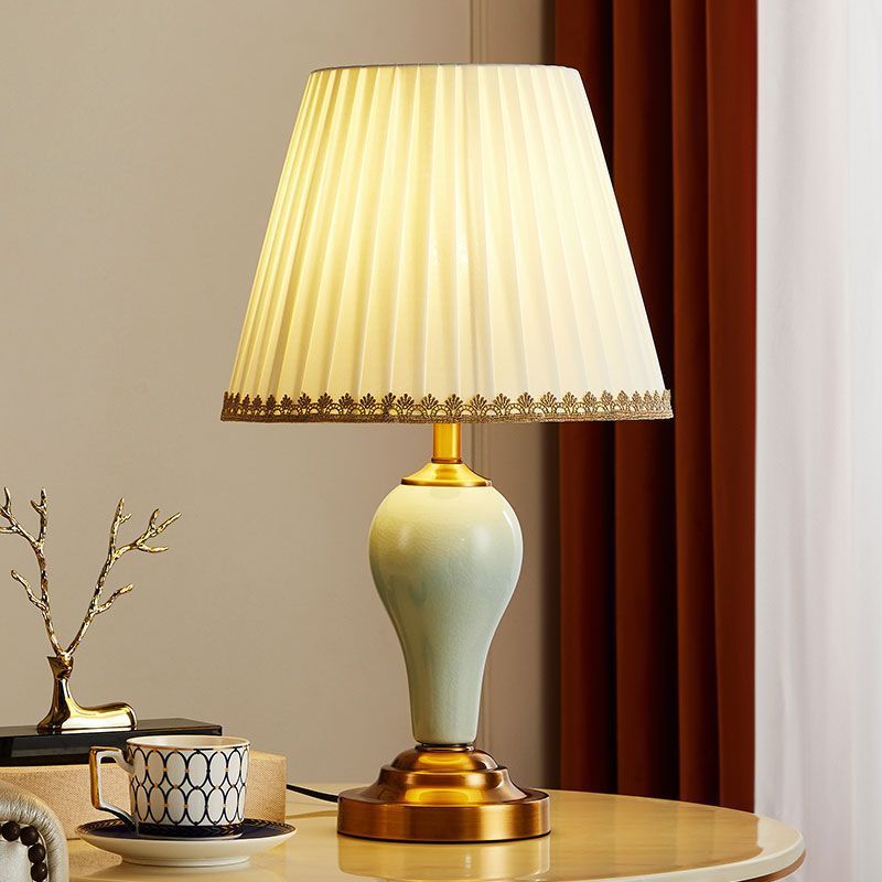 Celadon ceramic table lamp with brass-tone pedestal and pleated cream shade