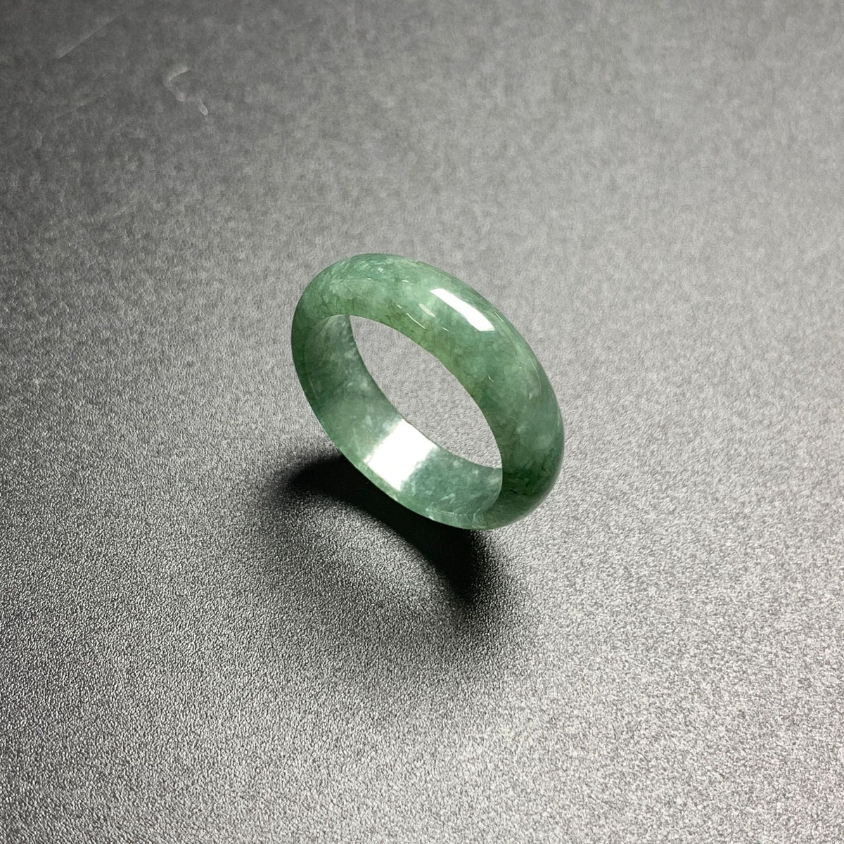 Polished green jadeite stone band ring with natural mottled translucency