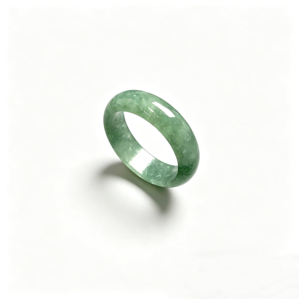Green jadeite ring photographed on white background showing smooth rounded band
