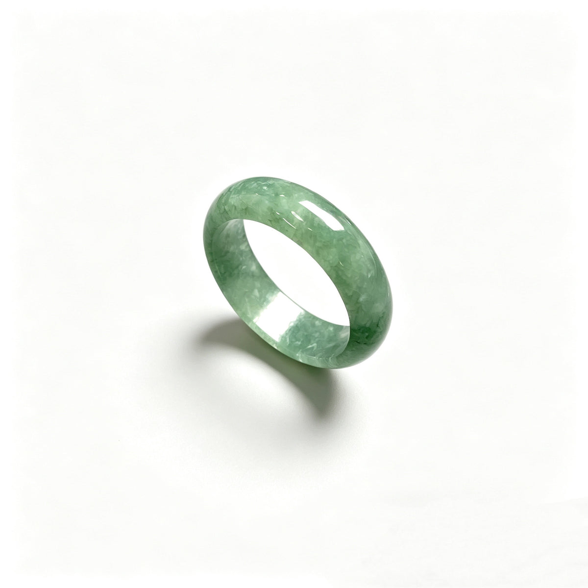 Green jadeite ring photographed on white background showing smooth rounded band