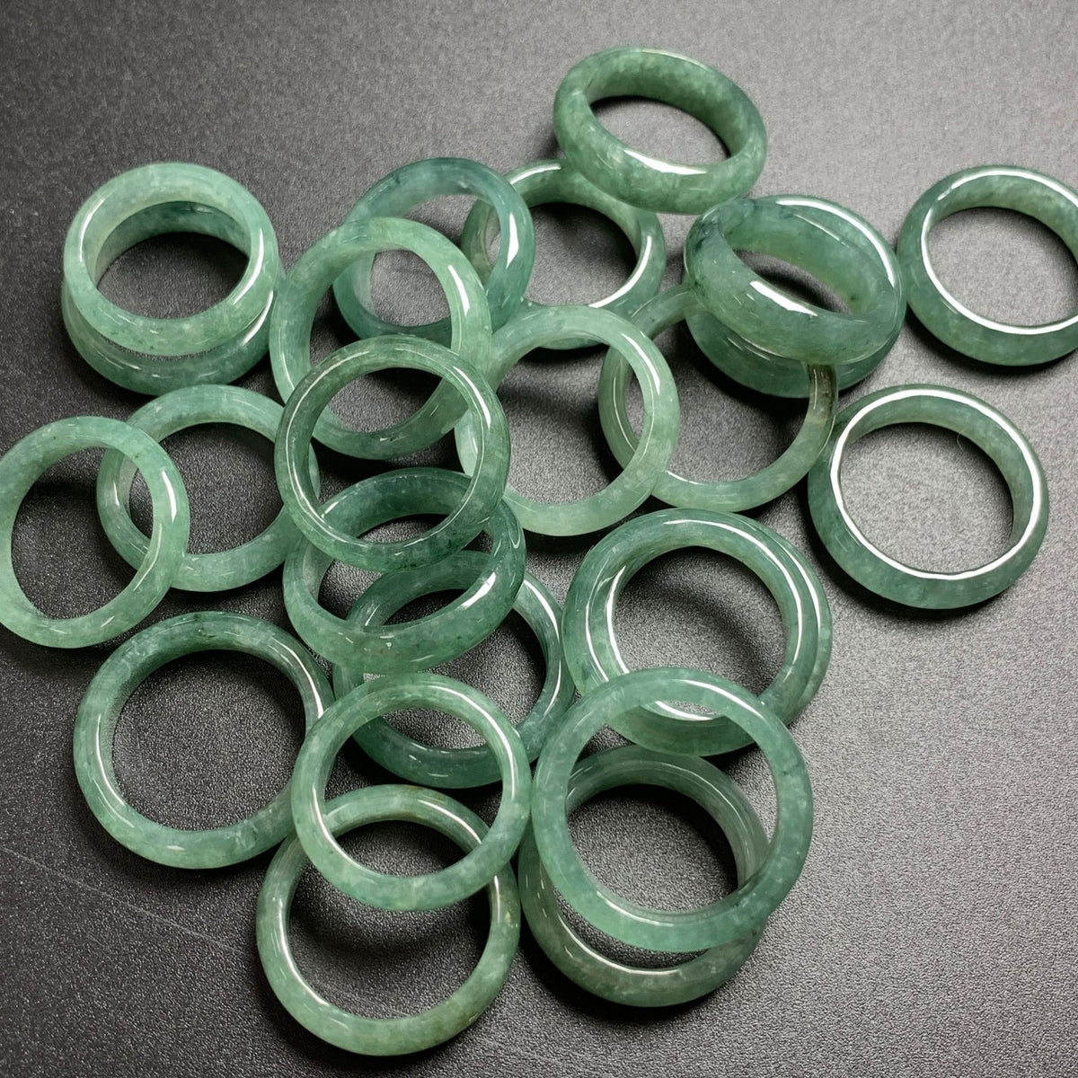 Multiple certified green jadeite band rings showing individual stone patterns