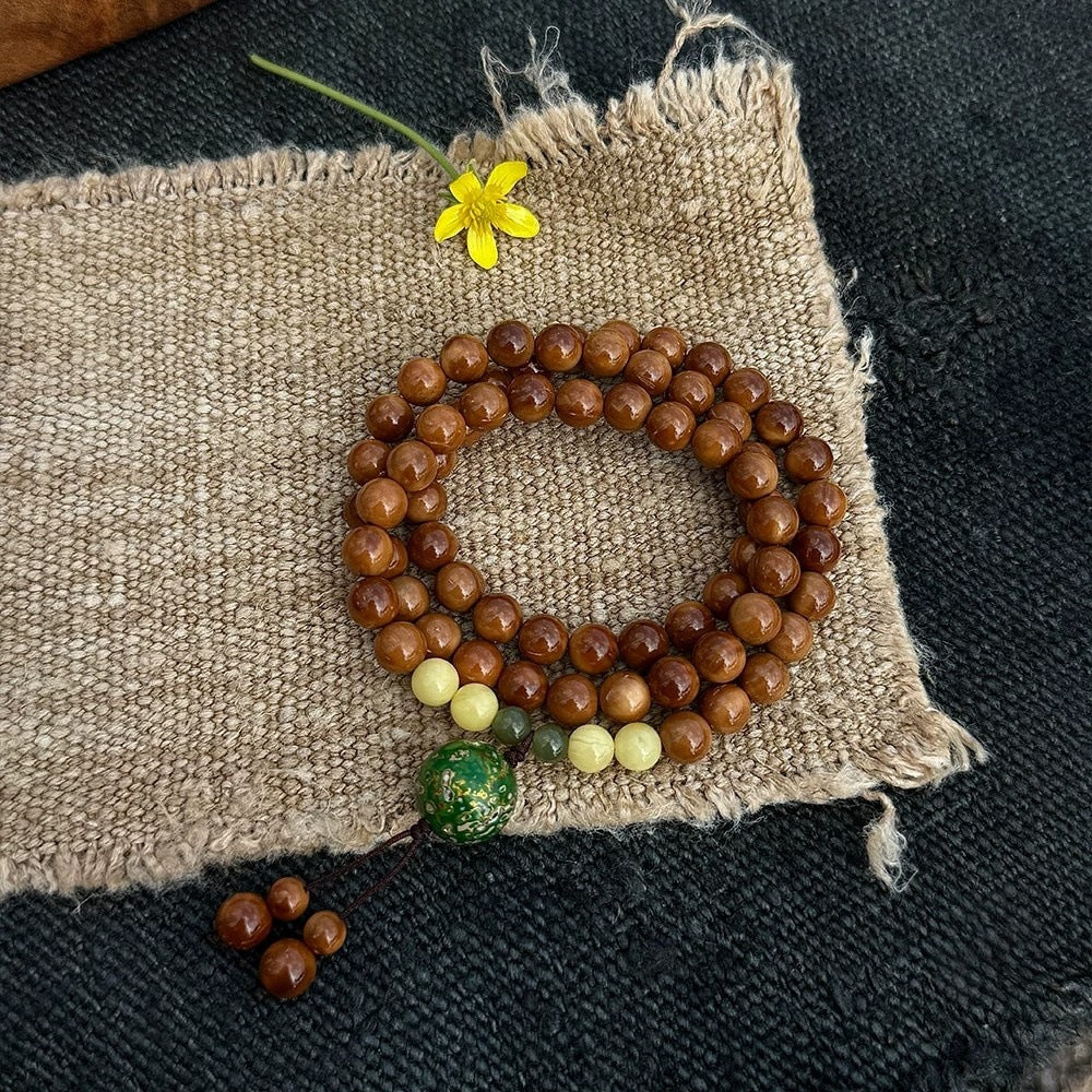 Chunhe Jingming Kuk Bodhi mala bracelet detail with warm brown seed beads and green decorative focal bead