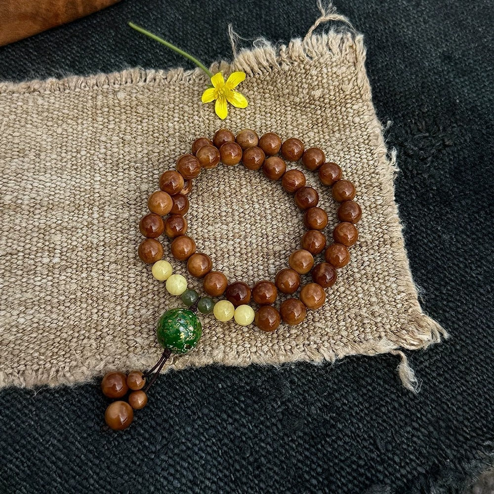 Chunhe Jingming Kuk Bodhi triple-wrap mala bracelet with polished brown beads, yellow-green accents and tassel-style drop