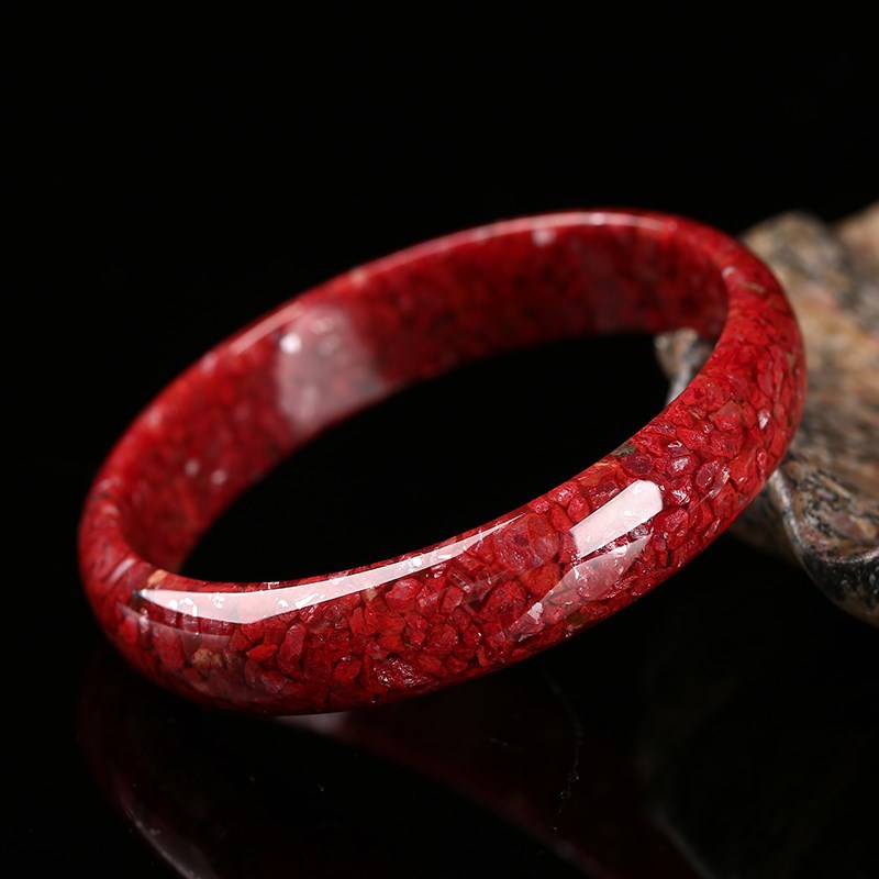 Polished cinnabar crystal-sand bracelet close-up under studio light