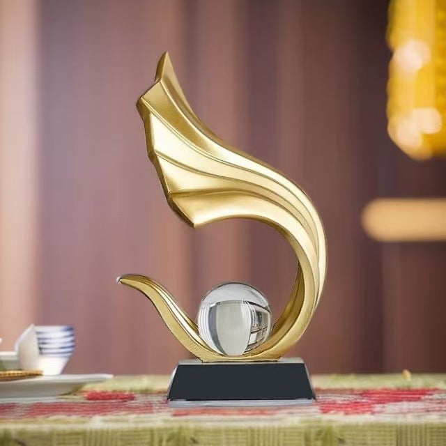 Gold abstract crystal ball sculpture with flowing flame silhouette