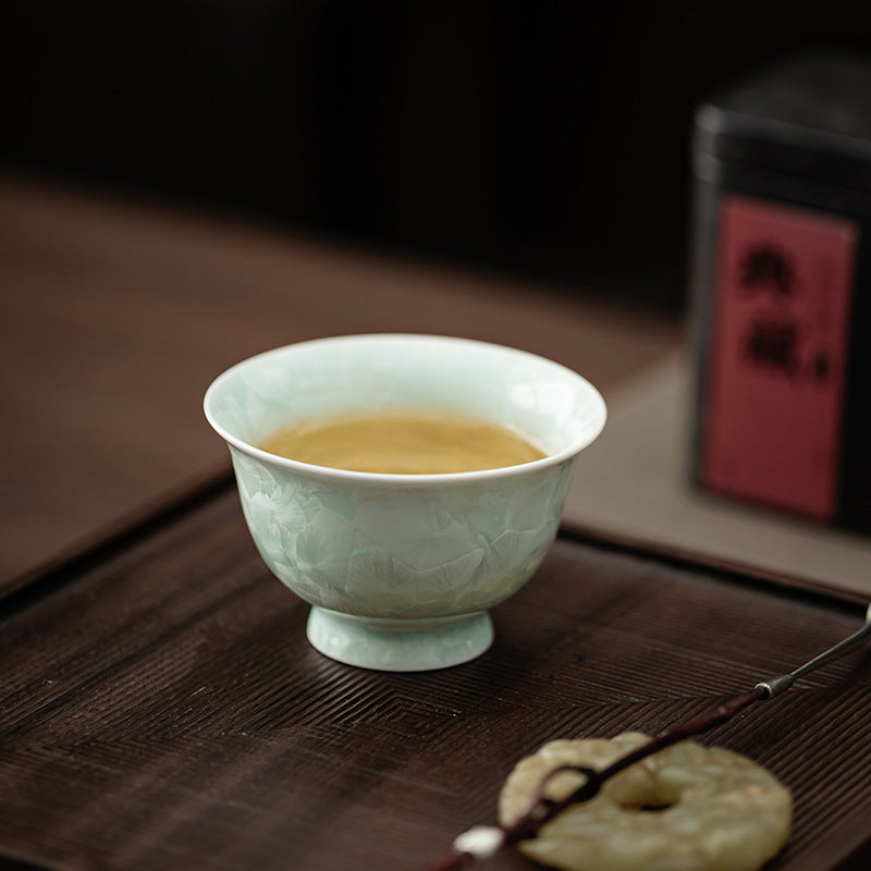 Celadon green crystalline glaze Gongfu tea cup with brewed tea on tea table