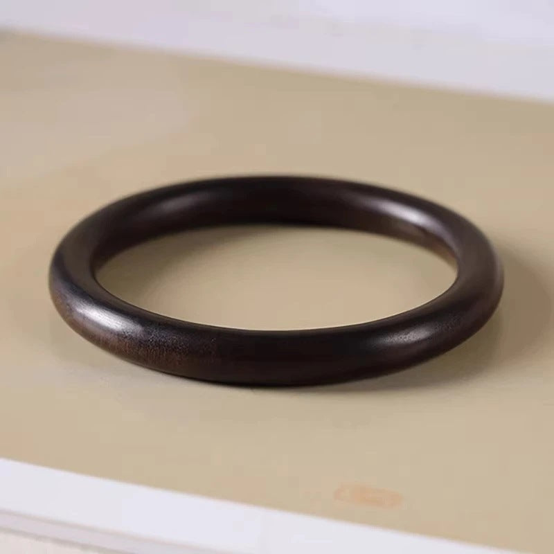Dark brown Chenxiang-style round wooden bangle bracelet shown in a close-up product view