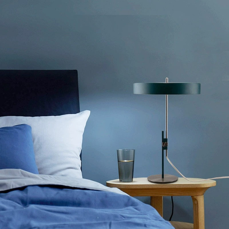 Dark green disc table lamp creating soft bedside ambient light