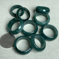 Deep green jadeite wide band rings with coin for scale and natural mottled pattern