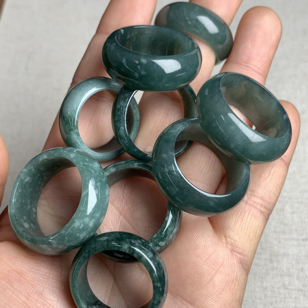 Deep green jadeite wide rings held in hand showing polished luster and stone variation
