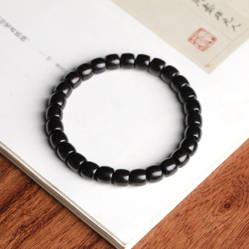 Blackwood-style direct-cut barrel bead bracelet displayed on a Chinese study book