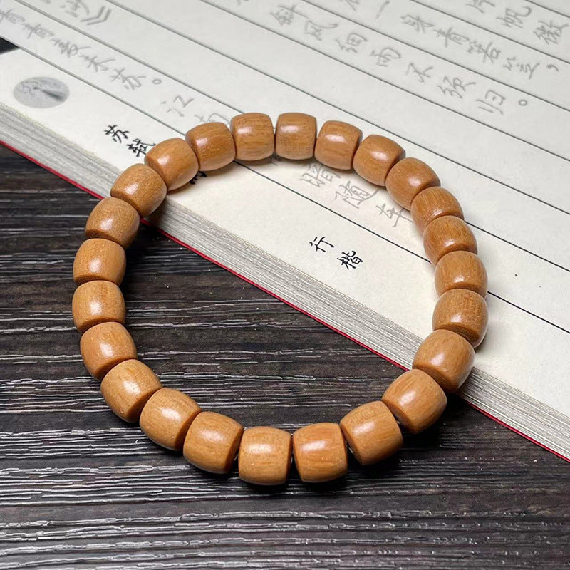 Light sandalwood-style direct-cut old-shape barrel bead bracelet on a Chinese study book