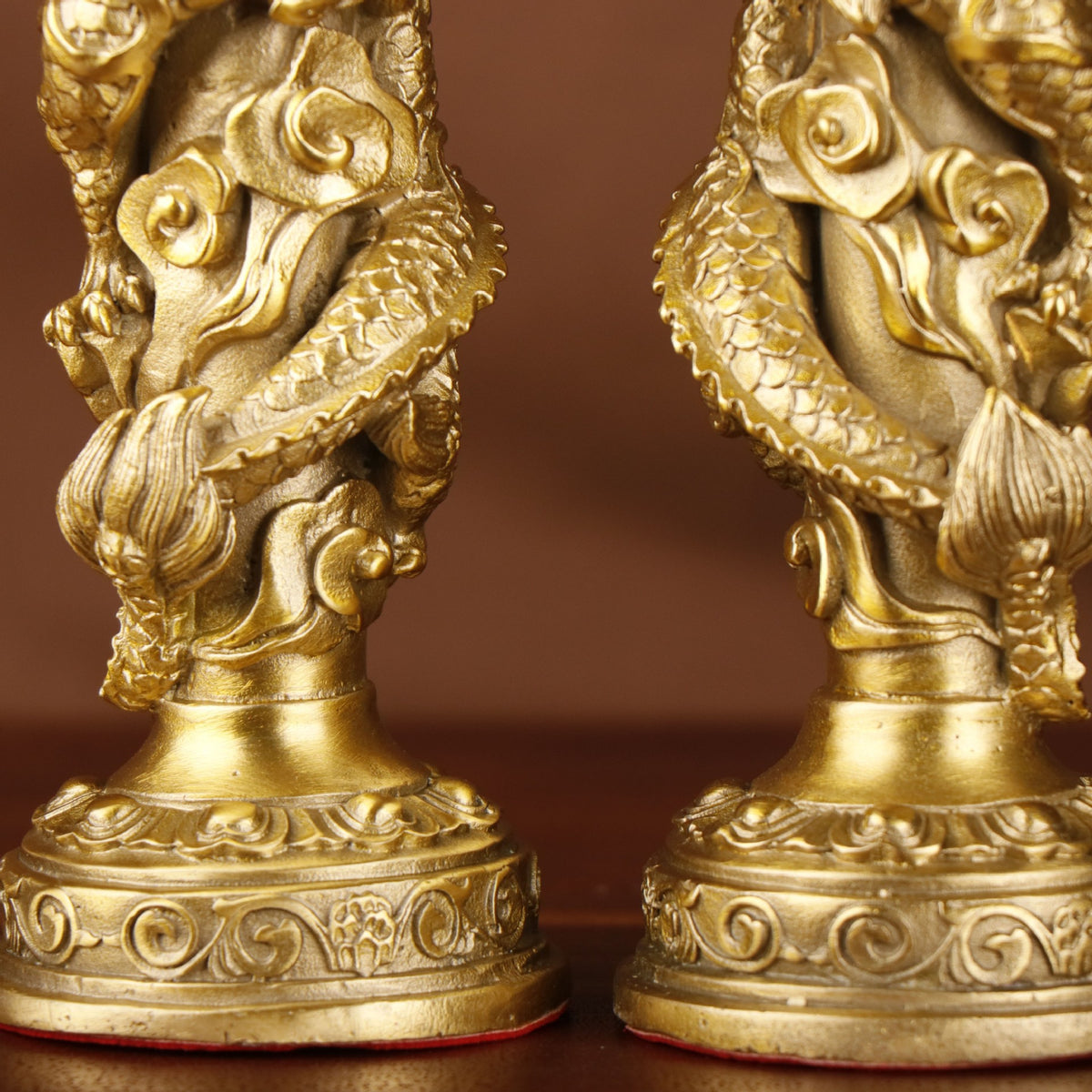 Close detail of Chinese double dragon copperware candlestick pair showing dragon scales, cloud scrolls, lotus forms and carved round bases