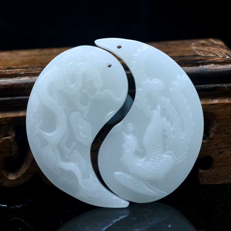 White stone dragon phoenix yin-yang pendant pair on dark wood background