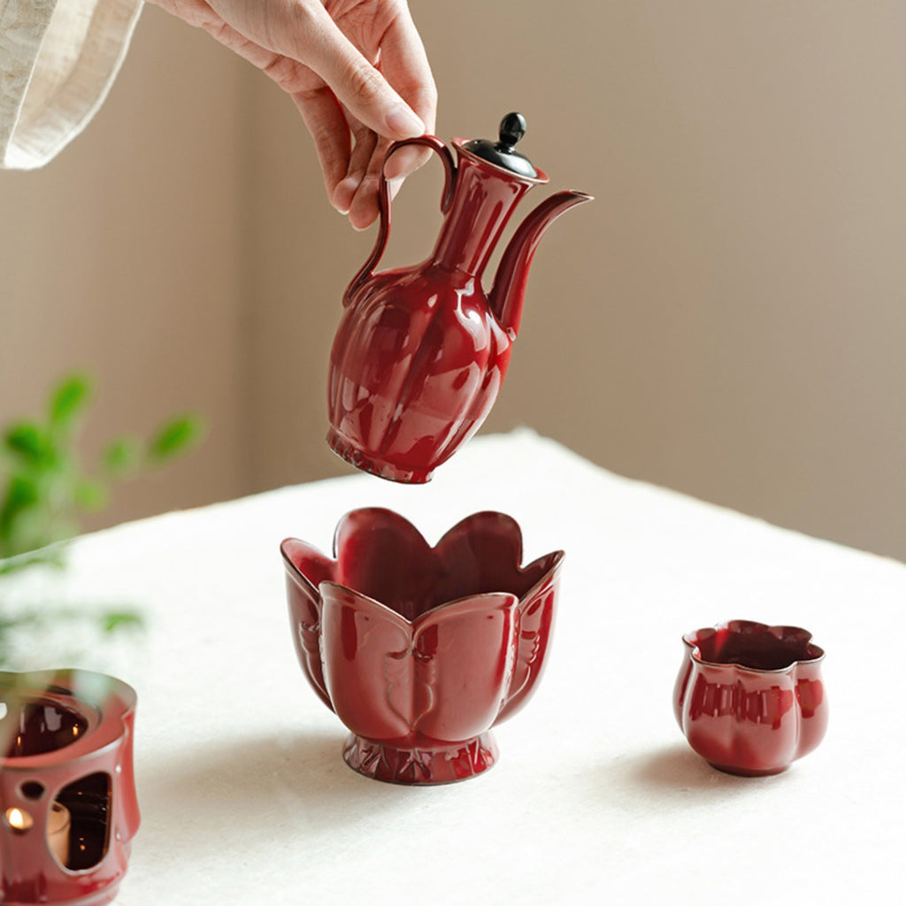 Red ceramic ewer styled with matching lotus-shaped warming bowl on a Chinese tea table