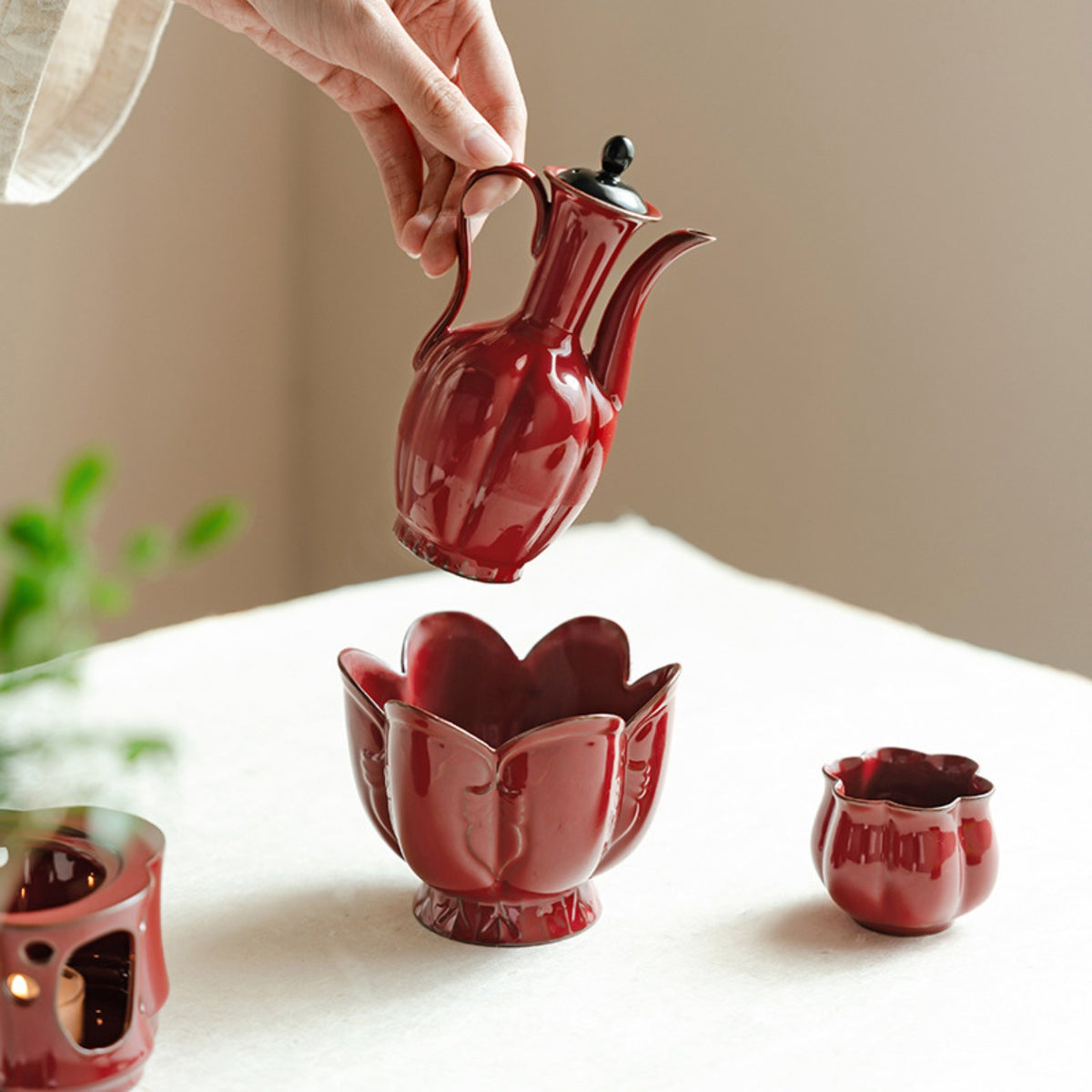 Red ceramic ewer styled with matching lotus-shaped warming bowl on a Chinese tea table