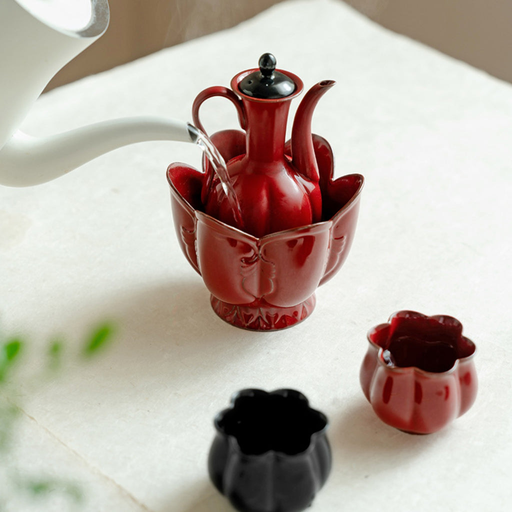 Red ceramic ewer placed in a lotus-shaped warming vessel with hot water being added