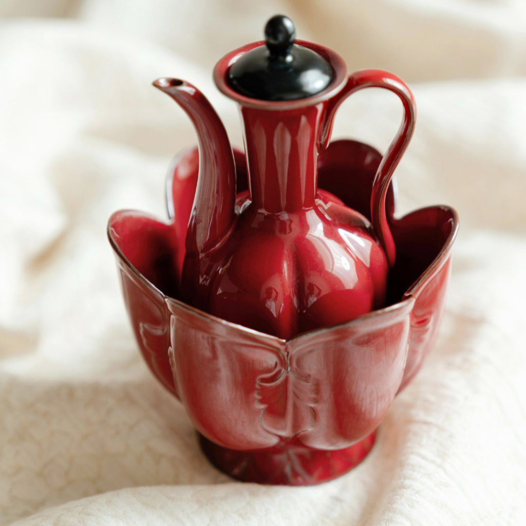 Close-up of glossy red ceramic ewer with matching lotus-petal warming vessel