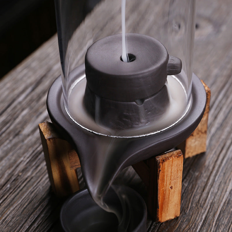 Close-up of smoke flowing through glass chamber into purple clay incense basin