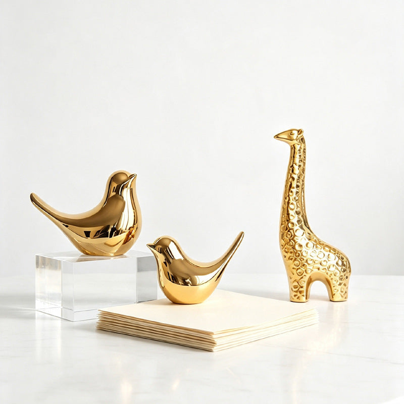 Gold ceramic birds and giraffe sculpture collection on white display