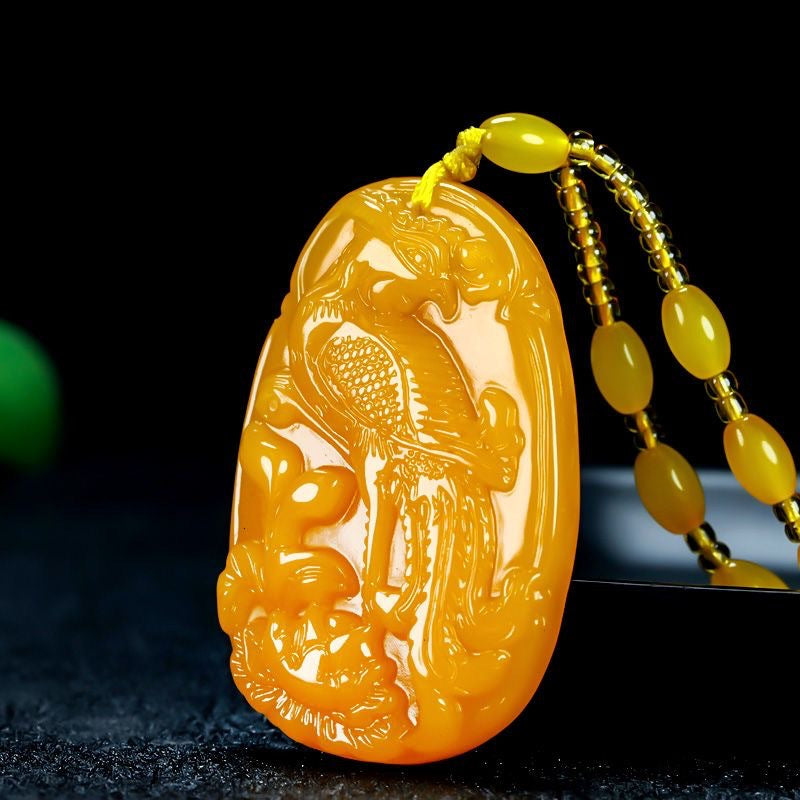 Golden phoenix pendant with bead cord on dark background