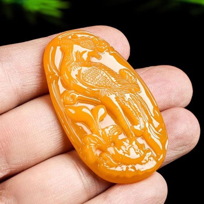 Polished yellow phoenix pendant held in hand for scale
