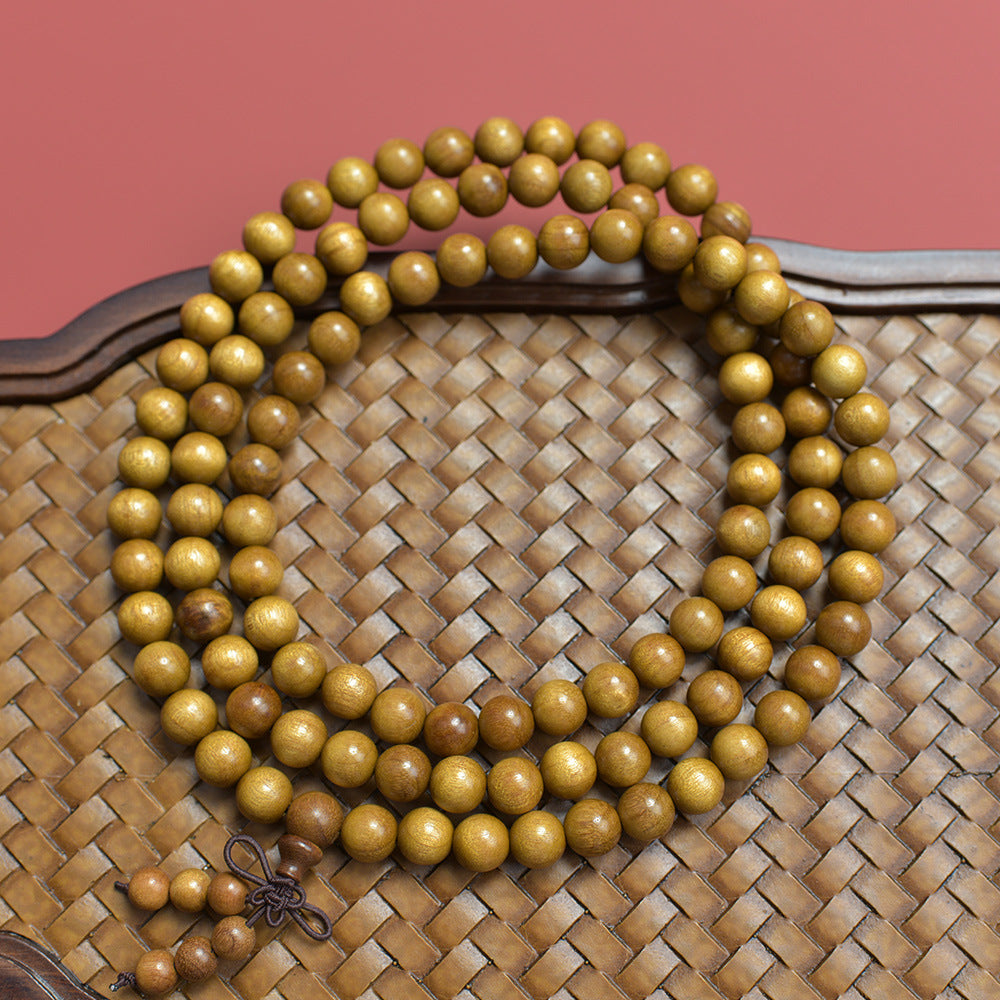 Golden-thread nanmu-style 108-bead wood mala displayed on a woven bamboo tea tray