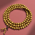 Golden-thread nanmu-style 108-bead wood mala with warm olive-gold grain on red background