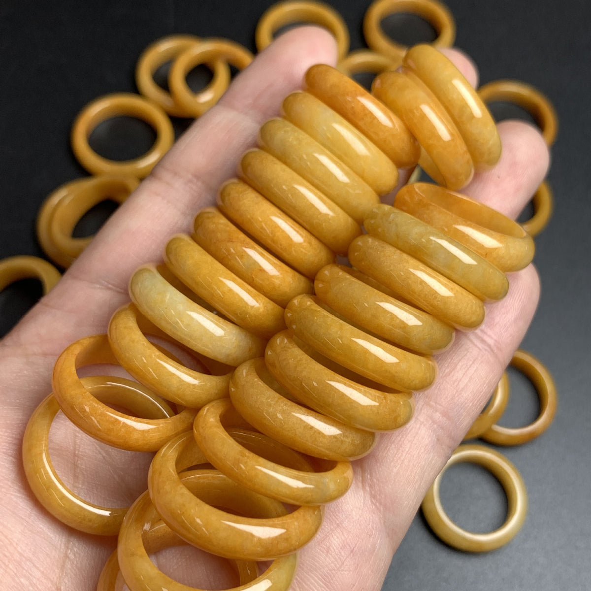 Golden yellow jadeite band rings held in hand showing rich honey tone